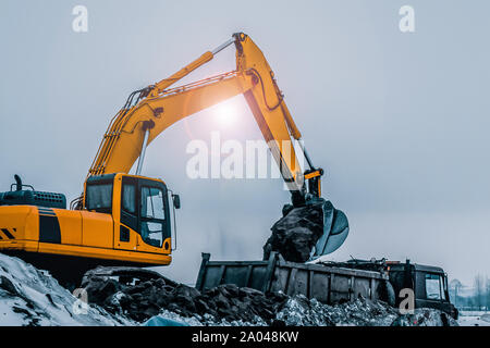 Alte Bagger mit Bagger Schaufel im Winter. Straßenbau im Schnee Stockfoto