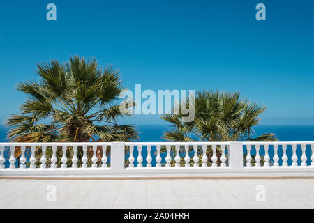 Meerblick Terrasse mit blauem Himmel und Palmen im Hintergrund Stockfoto