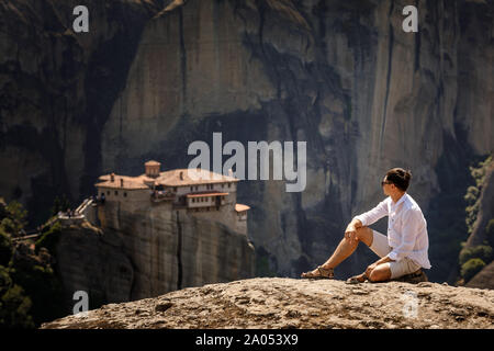 Touristische Frau sitzt auf der Spitze des Berges, auf landschaftlich reizvollen clif Hintergrund in der Nähe von Meteora Klöster in Griechenland. Stockfoto