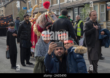 Immigranten britische muslimische Familie, Bradford 2010er Tag der Ashura-Parade schiitische Muslime erinnern sich an das Martyrium von Hussain. Vater und Söhne machen ein Selfie mit einem iPhone. 2019 West Yorkshire England HOMER SYKES Stockfoto