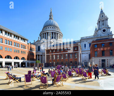 London, England, UK. Paternoster Square, hinter die St Paul's Kathedrale. Menschen in Liegestühlen während Ihrer Mittagspause Sitzung Stockfoto