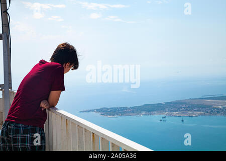 Junge Mann steht auf der Aussichtsplattform und blickt auf das Meer. Stockfoto