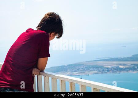 Junge Mann steht auf der Aussichtsplattform und blickt auf das Meer. Stockfoto