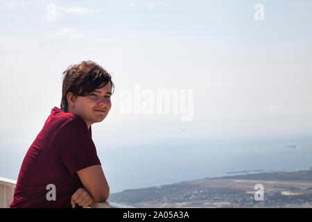 Junge Mann steht auf der Aussichtsplattform und blickt auf das Meer. Stockfoto