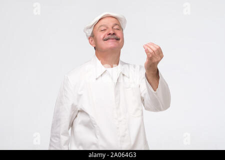 Gerne reife Hispanic Küchenchef ständigen anzeigen Geste Bedeutung perfekten Geschmack. Studio shot Stockfoto