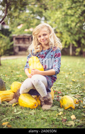 Schöne blonde Mädchen mit orange Kürbisse in grün herbst Garten Stockfoto