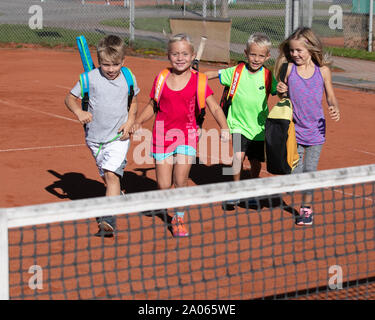 Kinder mit Taschen und rackets auf Tennisplatz Stockfoto