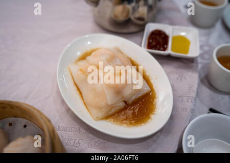 Hong Kong Stil Garnelen Reis Nudeln Rollen (Cheung Spaß) auf einem weißen Teller auf einem Tisch im Restaurant Stockfoto