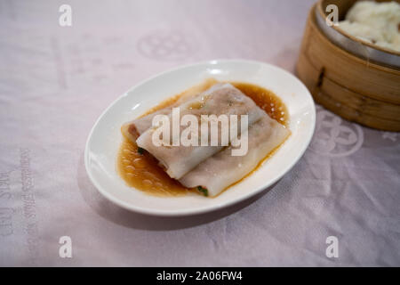 Hong Kong Stil Fleisch Reis Nudeln Rollen (Cheung Spaß) auf einem weißen Teller auf einem Tisch im Restaurant Stockfoto