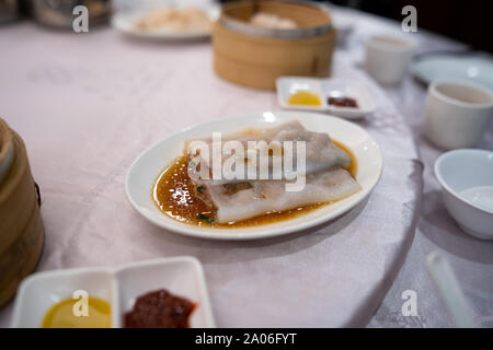 Hong Kong Stil Fleisch Reis Nudeln Rollen (Cheung Spaß) auf einem weißen Teller auf einem Tisch im Restaurant Stockfoto