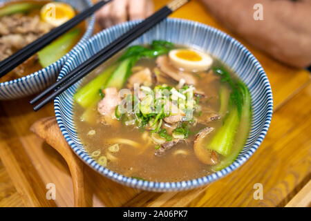 Taichung, Taiwan: eine Schüssel japanische Ramen Suppe mit in Scheiben geschnittenen Speck und weich gekochte Eier auf hölzernen Tisch. Stockfoto