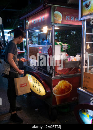 Mann Kaufen Ice Tea bei Nacht an einer Straße in einem taiwanesischen Nacht Marktstand Stockfoto