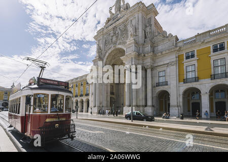 Lissabon, Portugal - August, 2019: alte Vintage touristische Straßenbahn vorbei an den typischen Straße mit Kopfsteinpflaster vor der Rua Augusta triumph arch Stockfoto