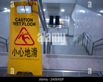 Kaohsiung, Taiwan: gelbe Achtung-nassen, rutschigen Schild mit Englisch und traditionellen chinesischen Text an der Vorderseite der eine Treppe nach unten in die U-Bahn Station Stockfoto