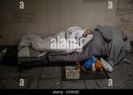 Eine obdachlose Frau schläft in einer U-Bahn zu U-Bahnhof Hyde Park Corner, London, England, Großbritannien Stockfoto