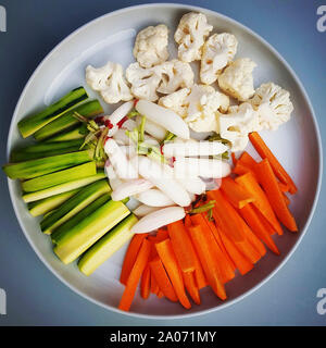 Nahaufnahme von Blumenkohl Karotten und Gurken in einem Teller auf dem Tisch unter den Lichtern. Stockfoto