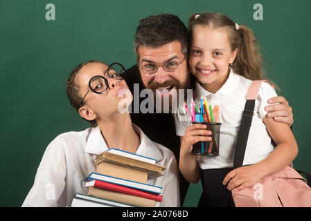 Ein Mädchen trägt einen schweren Stapel Bücher. Lehrer und Schüler mit schweren Buch Sammlung in den Händen. Stockfoto