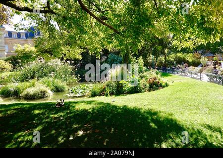 Leute sitzen auf Bänken und genießen Sie den Sonnenschein in Square du Temple - elie-wiesel, der englische Landschaftsgarten und der botanische Park, Paris, Frankreich. Stockfoto