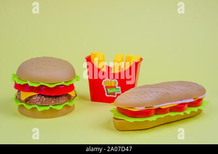 Fast food. Kunststoff Hamburger, Hot Dogs und Pommes frites auf gelbem Hintergrund Stockfoto