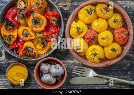 Gebackene rote und gelbe Tomaten und Paprika. Tomaten und Paprika in einer Auflaufform auf einem Holztisch. Ein gesundes und leckeres vegetarisches Gericht. Cl Stockfoto