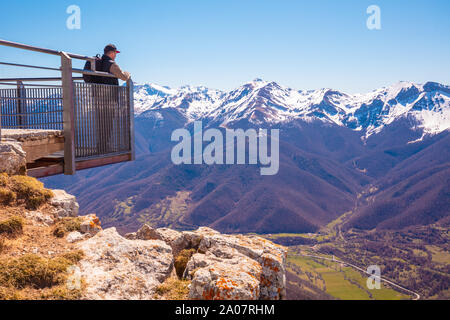 Ein Mann touristische steht auf einem Aussichtspunkt über das Tal gegen Berge bedeckt mit dem Schnee. Ein Mann sieht einen schönen Panoramablick auf die Berge. Nati Stockfoto