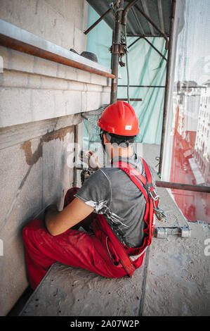 Mann Arbeiter auf Gerüst, die Arbeit an der Restaurierung der Fassade des alten Gebäudes durchführen. Reparieren und Renovieren Stockfoto