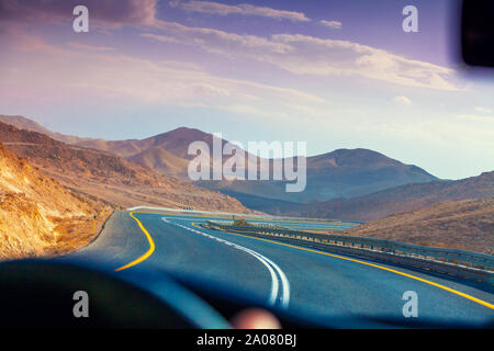 Das Autofahren auf den Berg Straße in die Wüste. Blick auf Sandstein Berge durch die Frontscheibe. Die Straße von Arad nach dem Toten Meer. Israel Stockfoto