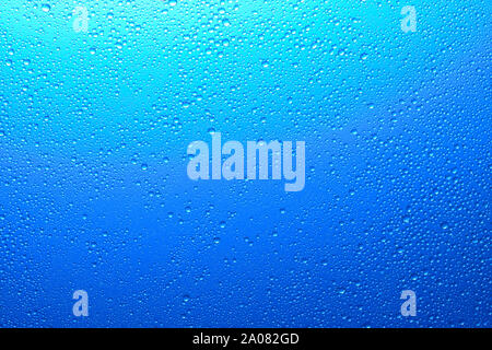 Glitzernde Wassertropfen auf einem durchscheinenden blauen Hintergrund mit Farbverlauf Farbe für eine Textur oder wallpaper Stockfoto