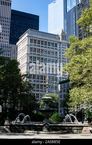 Bäume, Hochhäuser, Brunnen und Laterne im City Hall Park von NYC bin Morgen Stockfoto