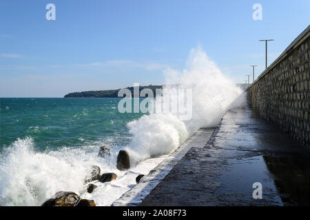 Meer Wellen auf einer Mole. Wanderweg entlang der groyne ist mit Meerwasser bei einem kleinen Sturm auf einem sonnigen Tag überschwemmt. Schwarze Meer. Stockfoto