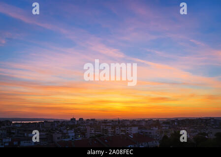Schöne skyscape am Sonnenuntergang über einer kleinen Stadt. Vivid Sky von golden und orange Farben beim Sonnenuntergang. Abend Landschaft. Schönheit in der Natur. Stockfoto
