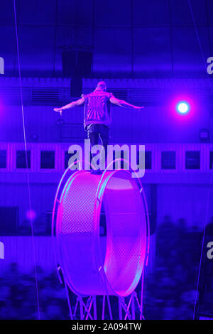 Circus performer/Acrobat auf das sich drehende Rad des Todes/Space Wheel. Gefährliche Arbeit. Stockfoto