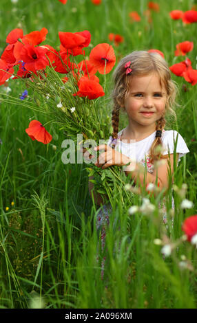 Drei Jahre altes Kleinkind Mädchen im Sommer Feld der blühenden Mohn Blumen mit einem Blumenstrauß posing Stockfoto