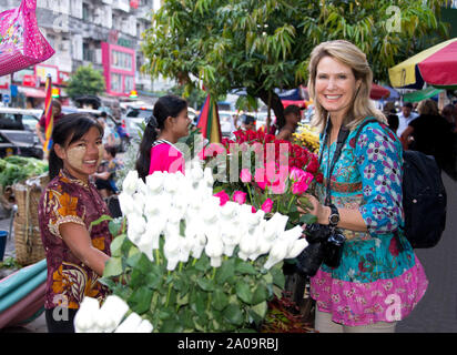 Kaukasische weibliche Touristen, ist Model Released und eine traditionelle burmesische Frauen Anbieter mit thanaka Make-up, die Blumen im Freien Markt Stockfoto