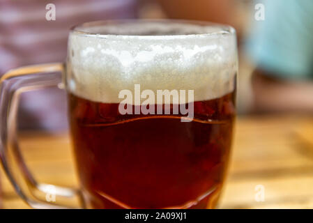 Der Mensch ist ein frisch gezapftes Glas Bier in der Hand Stockfoto