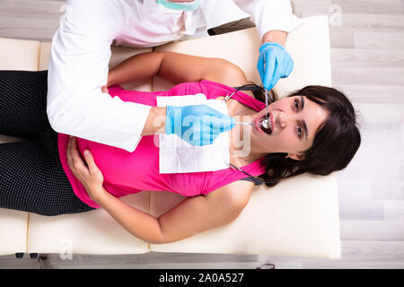 Ein männlicher Zahnarzt Behandlung der Zähne von jungen schwangeren Frau Patient in der Klinik Stockfoto