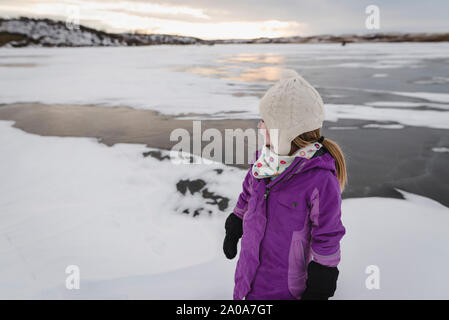 Kleines Mädchen spielt auf gefrorenem See Stockfoto