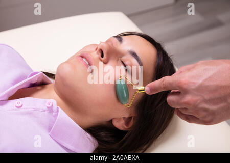 Entspannt schöne junge Frau, Gesichts Gua Sha Massage mit Gesichts Jade im Spa Stockfoto