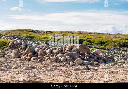 Eine Handvoll von riesigen Steinen von Gras umgeben. Hellen Himmel in den Wolken. Hügeln im Hintergrund. Stockfoto