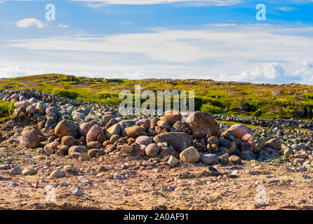 Eine Handvoll von riesigen Steinen von Gras umgeben. Hellen Himmel in den Wolken. Hügeln im Hintergrund. Stockfoto