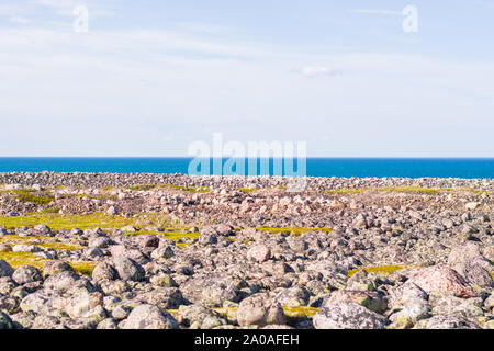 Felsigen Küste. Riesige Geröll am Strand. Der Barentssee schimmert in allen Schattierungen von Blau im Sommer. Unter den Steinen können Inseln o gesehen werden. Stockfoto