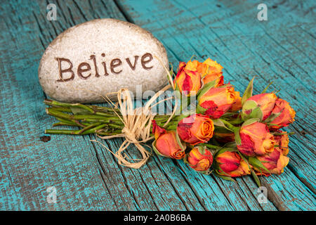 Glauben Text auf Rock mit orange Rose Bouquet auf rustikalen Türkis lackiertes Holz Stockfoto