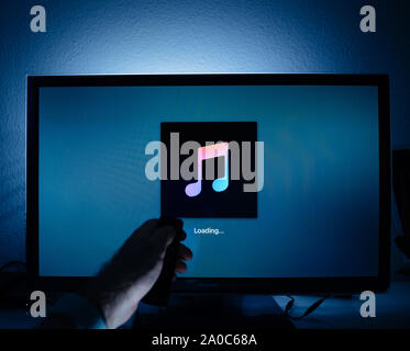 Paris, Frankreich, ca.2019: Mann surfen mit Remote Apple TV-Menü auf Panasonic Plasma tv Wohnzimmer laden Botschaft von Apple Musik streaming Service Stockfoto