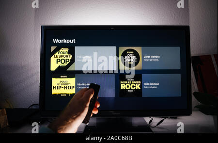 Paris, Frankreich, ca.2019: Mann surfen mit Remote Apple TV-Menü auf Panasonic Plasma tv Wohnzimmer mit Workout Playlisten Pop, Rock, Hip-Hop in allen Genres große Playlist von Apple Musik Stockfoto