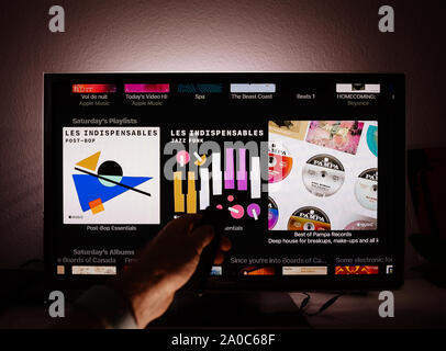 Paris, Frankreich, ca.2019: Mann surfen mit Remote Apple TV-Menü auf Panasonic Plasma tv Wohnzimmer surfen für die Artist's Playlisten Samstag Playlists Jazz, Funk, post-bop, Stockfoto