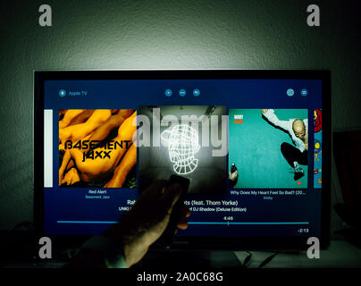 Paris, Frankreich, ca.2019: Mann surfen mit Remote Apple TV-Menü auf Panasonic Plasma tv Wohnzimmer surfen für die Künstler Playlisten Elektronische Musik Stockfoto