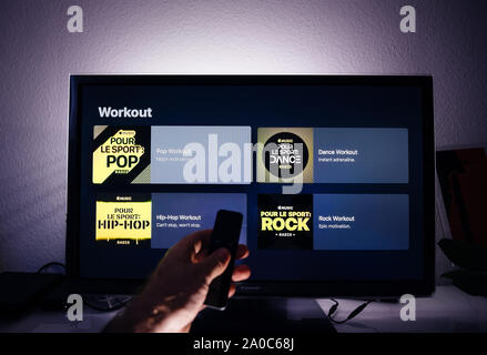 Paris, Frankreich, ca.2019: Mann Hand remote Apple TV-Menü auf Panasonic Plasma tv Wohnzimmer mit Workout Playlisten Pop, Rock, Hip-Hop in allen Genres große Playlist von Apple Musik Stockfoto
