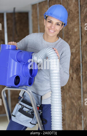 Weibliche Elektriker bei der Verkabelung an der Decke im Innenbereich Stockfoto