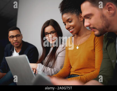 Lächelnd diverse Freunde Social Networking auf einem Laptop Computer zusammengefasst lesen die neuesten Informationen auf dem Bildschirm Stockfoto