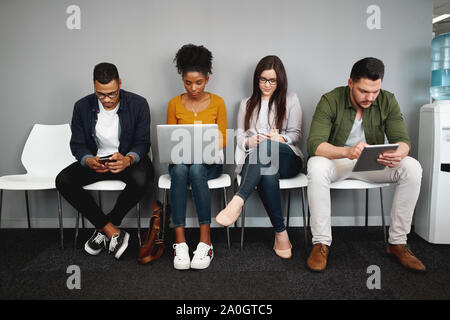 Vielfältige arbeit Kandidaten sitzen in der Warteschlange im Amt für Job Interview mit modernen Gadgets Vorbereitung für die Personalbeschaffung Stockfoto